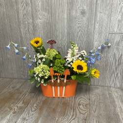Flower arrangement in an orange container with small garden tools