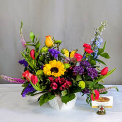 Colorful mixed flower arrangement in a white basket with a butterfly pick