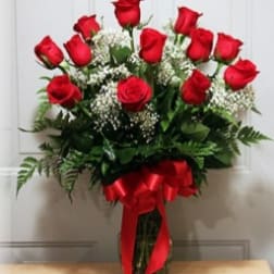Bouquet of red roses with baby's breath in a glass vase tied with a red ribbon