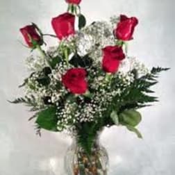 Red roses arranged in a clear glass vase with baby's breath