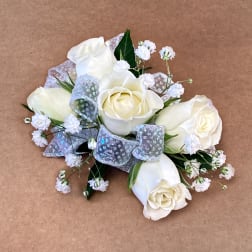 White rose bouquet with silver ribbon accents on a brown background