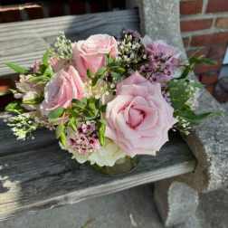 Pink roses arranged in a low glass vase with small filler flowers