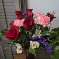 Bouquet of red roses, pink carnations, and white flowers in a vase