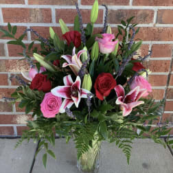 Mixed bouquet of pink and red roses with lilies in a glass vase