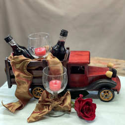 Decorative truck with wine bottles, glass candle holders, and a red rose