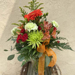 Mixed bouquet in a glass vase with red, green, and peach flowers