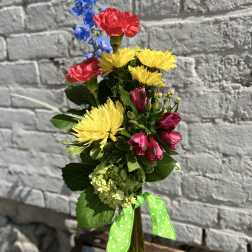 Colorful mixed bouquet in a tall glass vase with a green ribbon