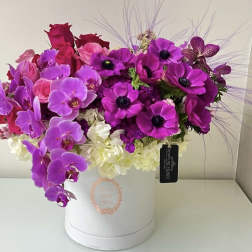 Pink and purple floral arrangement in a white hat box