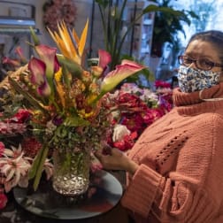 Woman holding a colorful floral arrangement in a glass vase