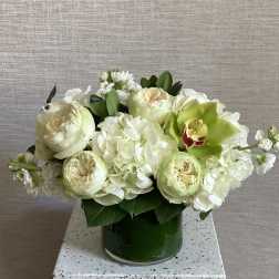 White and pale green floral arrangement in a green vase