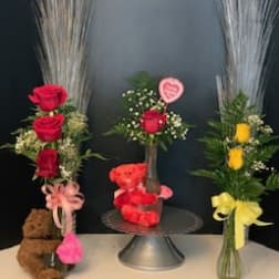 Three rose arrangements with teddy bears and ribbons