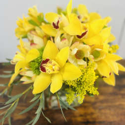 Yellow orchid bouquet with green filler in a glass vase