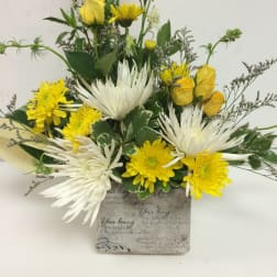 Yellow roses and white chrysanthemums in a decorative sympathy vase