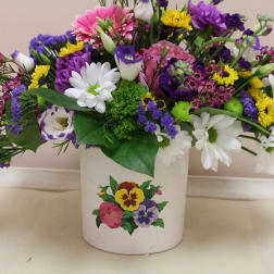 Mixed bouquet in a white ceramic pot with white, purple, pink, and yellow flowers