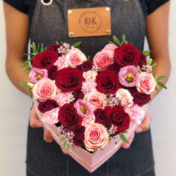 Heart-shaped box of red and pink roses held by a person