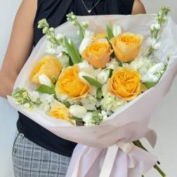 Bouquet of yellow roses and white flowers wrapped in pale pink paper