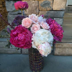 Pink and white peonies with small roses in a dark vase