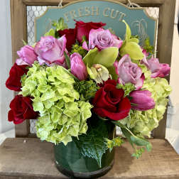 Bouquet of red and pink roses with green hydrangeas in a glass vase