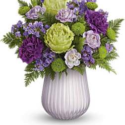 Purple and green floral arrangement in a ribbed glass vase