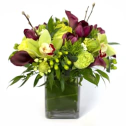 Bouquet of green and burgundy flowers in a square glass vase