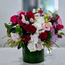 Mixed bouquet of red, pink, and white flowers in a green glass vase