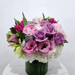 Pink and purple bouquet in a ribbed glass vase