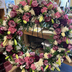 Large floral wreath with pink roses, lilies, and white blooms on a stand