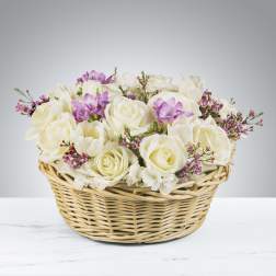 Low basket of white roses with touches of lavender and pink flowers