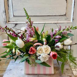 Mixed bouquet of tulips, roses, and snapdragons in a pink striped box