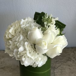 White roses and hydrangeas arranged in a green vase