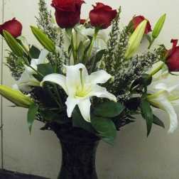 Bouquet of red roses and white lilies in a dark vase