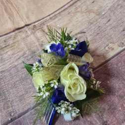 Small bouquet with white roses, blue flowers, and gold ribbon