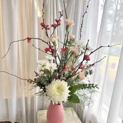 Tall floral arrangement in a pink vase with white and pink blooms