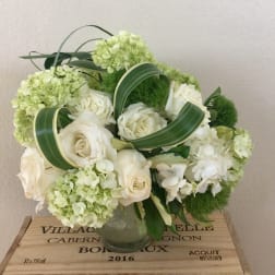 White roses and pale green hydrangeas arranged in a glass vase