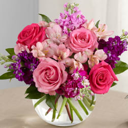 Pink and purple bouquet of roses and alstroemeria in a clear glass vase