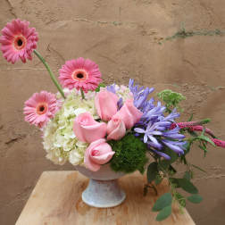 Pink roses and gerbera daisies in a pedestal vase