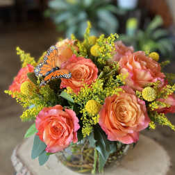 Bouquet of coral roses with yellow filler flowers in a glass vase