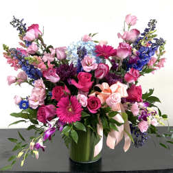 Large mixed bouquet of pink, purple, and blue flowers in a glass vase