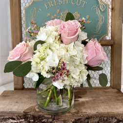 Pink roses and white hydrangeas in a clear glass vase