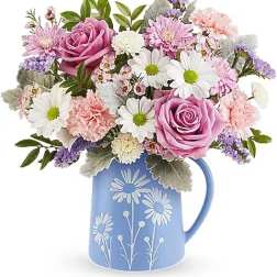 Pink and white flower bouquet in a blue pitcher vase