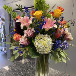Mixed bouquet of roses, lilies, and hydrangea in a glass vase
