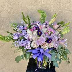 Lavender and blush mixed bouquet in a glass vase with a purple ribbon