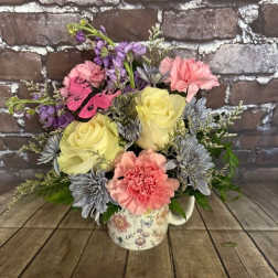 Bouquet of pastel flowers in a floral mug with a butterfly accent