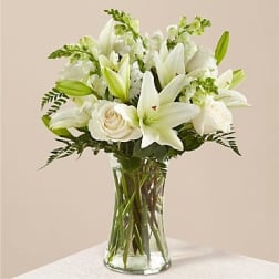 White lilies and roses arranged in a clear glass vase