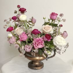 Pink and white mixed flowers arranged in a bronze urn vase
