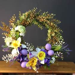 Floral wreath with yellow and purple flowers and pastel eggs