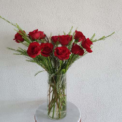 Red roses in a clear glass vase with airy greenery