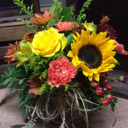 Mixed bouquet with a sunflower, yellow rose, and pink carnation in a rustic container