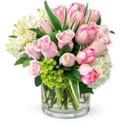 Pink roses and tulips arranged in a clear glass vase