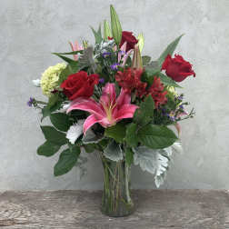 Bouquet of red roses and pink lilies in a clear glass vase